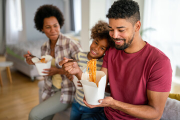 Happy african family eating at living room and enjoying time together. Home delivary takeaway food