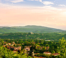 travel summer view from hill to a nice european town with amazing buildings, green hills and mountains with amazing cloudy evening sky on background