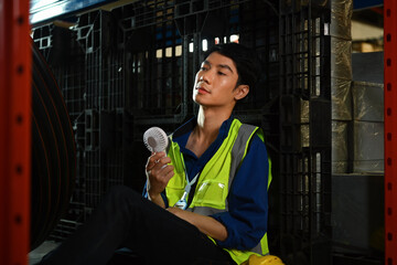 Exhausted man warehouse worker sitting in on floor feeling tired from hard work and hot temperature