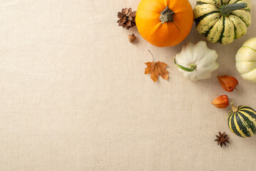 Warm and inviting Thanksgiving display: Top view of beige tablecloth arrangement, accompanied by pumpkins, pattypans, physalis, acorn and anise. Your text or message can grace this space