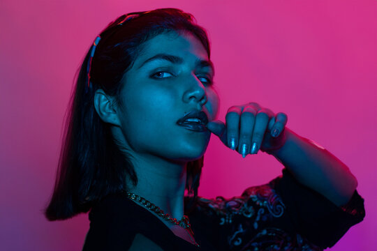 Caucasian young woman's portrait on gradient background in neon light. Beautiful female model with unusual look. Concept of human emotions, facial expression, sales, ad. Looking ar side, smiles