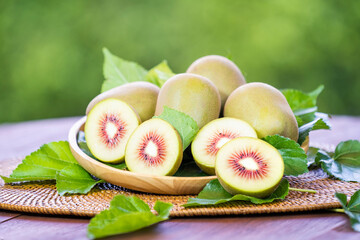 Red Kiwi on wooden basket, Kiwi Fruit and sliced kiwi with leaf on green bokeh background.