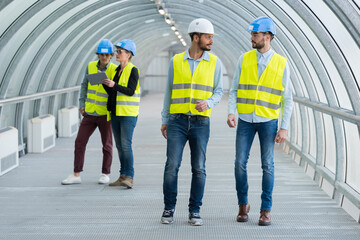 workers in high-visibility vests walking through tunnel