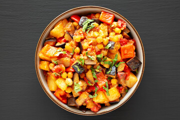 Homemade Eggplant Potato Tomato Stew with Parsley in a Bowl on a black background, top view.