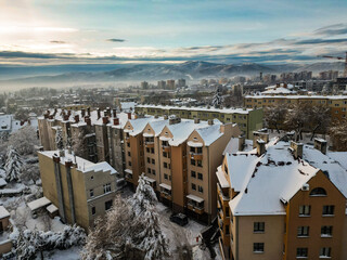Budynki i bloki mieszkalne miasta Bielsko-Biała w zimie widoczne z lotu ptaka, w tle góry Beskidu i lekko zachmurzone niebo 