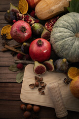 Fototapeta na wymiar Vertical Top-Down View of Autumnal Fruits. Figs, Hazelnuts, Pomegranates, and Pumpkin