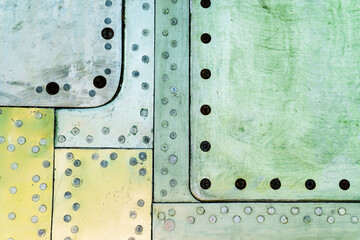 Fragment of the skin of an old plane. Metal background with screws and rivets in green and yellow colors. Blank for the designer. flat lay frame