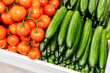 Cucumbers and tomatoes on the counter in a store. Trade in fresh vegetables in retail chains and at the market. Close-up. Selective focus