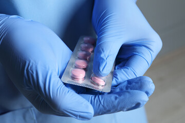 Doctor taking pill out from blister pack on grey background, closeup
