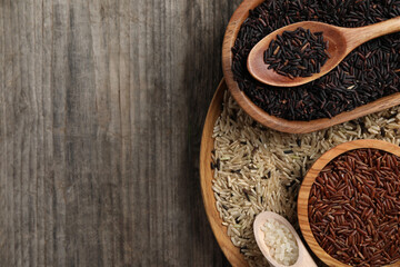 Different sorts of rice on wooden table, flat lay. Space for text