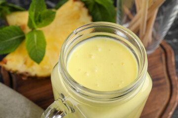 Obraz na płótnie Canvas Tasty pineapple smoothie in mason jar on table, closeup
