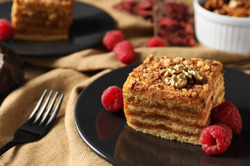 Pieces of delicious layered honey cake with nuts and raspberries served on table, closeup. Space for text - Powered by Adobe