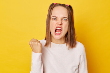 Teenage girl in jumper with ponytails clenches fist and teeth expresses negative emotions being fed...