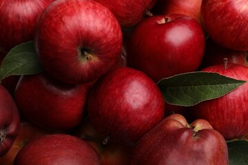 Fresh red apples and leaves as background, top view