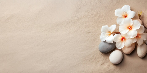 Natural sand background with flowers and stones arrangement. Wellness, beauty or zen meditation wallpaper with copy space.