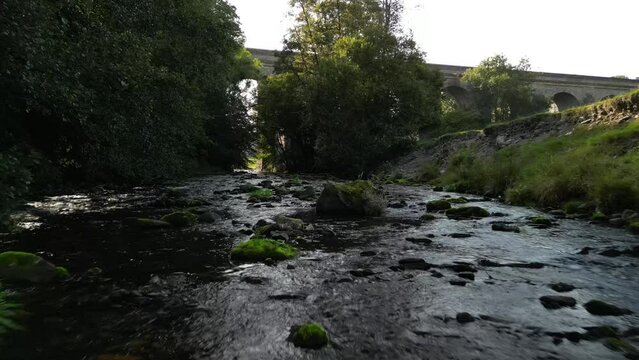 Babbling Brook drone low flyover in slo-mo,  Chirk Aqueduct Approach - River Ceiriog, Chirk, Wales UK - hazy summer afternoon - Sept 23