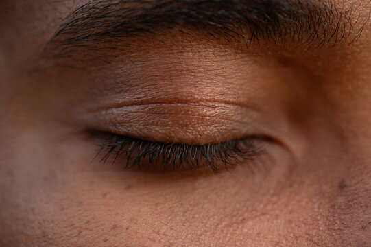 Close-up of a closed eye of a young African man, black lashes, detailed skin texture
