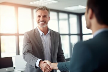 a smiling 40-year-old businessman shaking hands with his partner after signing an agreement during an office meeting