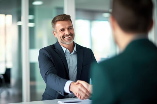 a smiling 40-year-old businessman shaking hands with his partner after signing an agreement during an office meeting