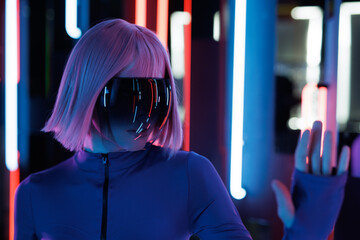 Woman in futuristic costume with flowing hair. Female in modern VR glasses interacting with network while having virtual reality experience. Augmented reality game, future technology, AI concept. VR. 