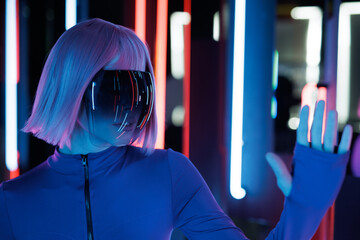 Woman in futuristic costume with flowing hair. Female in modern VR glasses interacting with network while having virtual reality experience. Augmented reality game, future technology, AI concept. VR. 