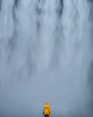 Mężczyzna stoi na tle wodospadu Skogafoss, Islandia - obrazy, fototapety, plakaty