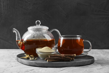 Aromatic licorice tea, dried sticks of licorice root and powder on light gray textured table - obrazy, fototapety, plakaty
