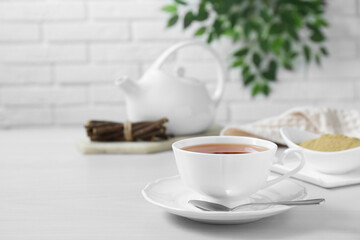 Aromatic licorice tea in cup served on white table, space for text