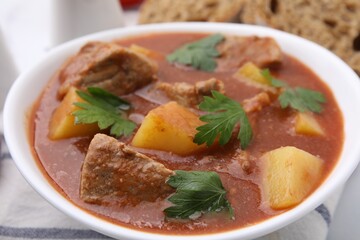 Delicious goulash in bowl on table, closeup