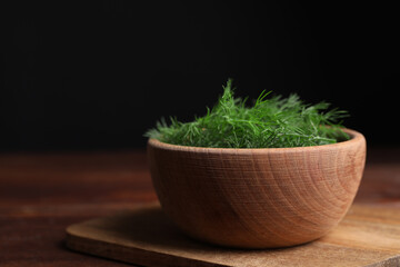 Bowl of fresh dill on wooden table, closeup. Space for text