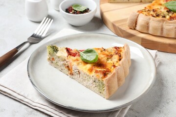 Piece of tasty quiche with chicken, vegetables, basil and cheese served on light table, closeup