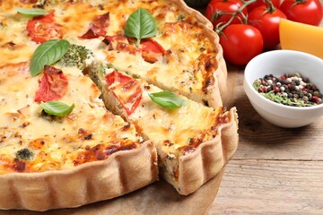 Tasty quiche with tomatoes, basil and cheese served on wooden table, closeup