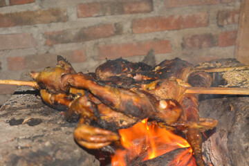Photo of traditional Indonesian food, a rooster being grilled with billowing smoke
