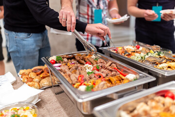 People choosing fresh prepared food from buffet table.