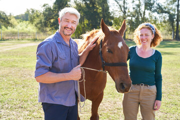 Man and woman holding horse on ranch