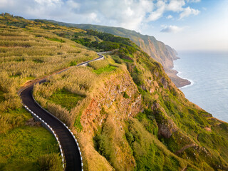 Aerial view of a narrow coastal road during the sunset. Winding path in the western part of the Madeira Island, Portugal, Europe.