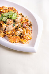 local traditional chinese stir wok fried big fresh oyster seafood with crispy chicken egg omelette in plate on wood table asian restaurant banquet cuisine halal food menu