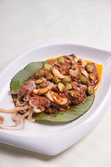 grilled bbq fresh whole seafood squid sooting octopus with spicy samba chilli sauce and petai smelly bean vegetables in banana leaf plate on wood table asian restaurant banquet cuisine halal food menu