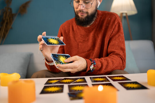 Young male fortune-teller with tarot cards recording video for blog at home.