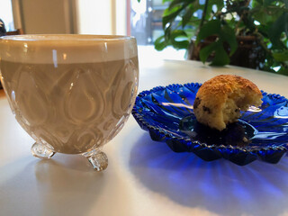 ein kleines antikes Glas mit einem Cafe Latte und Kuchen