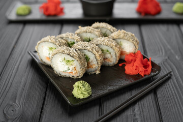 Hot tempura sushi roll with seafood on black wooden background.