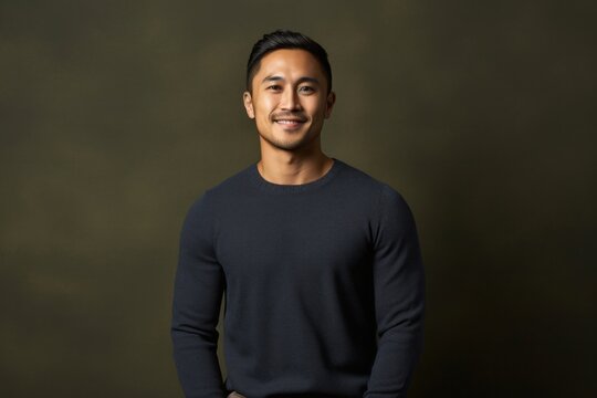 portrait of a confident Filipino man in his 30s wearing a chic cardigan against an abstract background