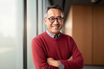 portrait of a confident Filipino man in his 50s wearing a chic cardigan against a white background