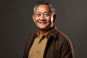 Fototapeta premium portrait of a confident Filipino man in his 70s wearing a chic cardigan against an abstract background