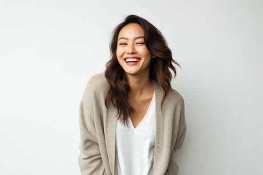 portrait of a confident Filipino woman in her 20s wearing a chic cardigan against a white background