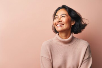 portrait of a confident Filipino woman in her 40s wearing a cozy sweater against a pastel or soft colors background