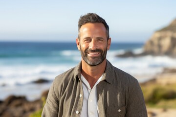portrait of a confident Israeli man in his 40s wearing a chic cardigan against a beach background