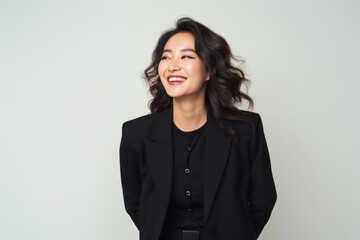 portrait of a confident Japanese woman in her 30s wearing a classic blazer against a minimalist or empty room background