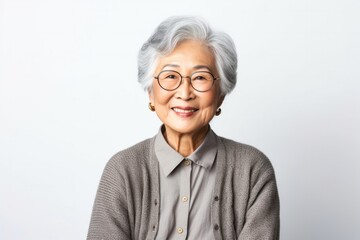 portrait of a confident Japanese woman in her 90s wearing a chic cardigan against a white background