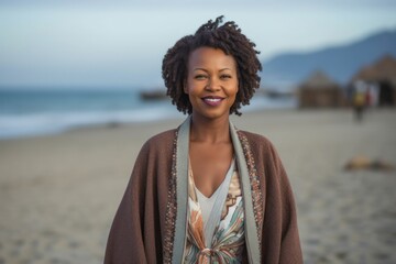 portrait of a confident Kenyan woman in her 40s wearing a chic cardigan against a beach background